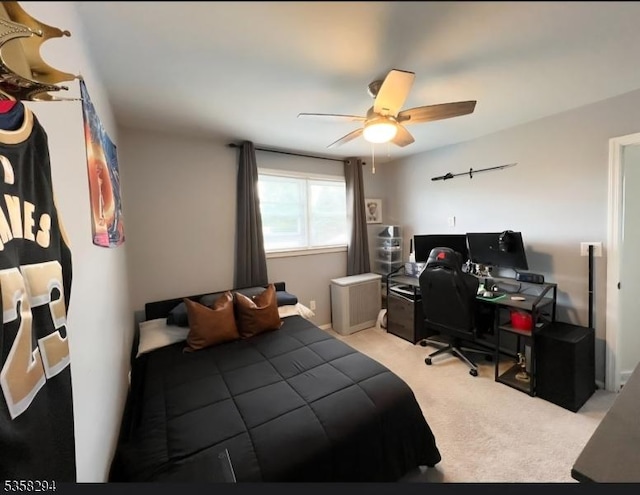 carpeted bedroom with an office area and ceiling fan