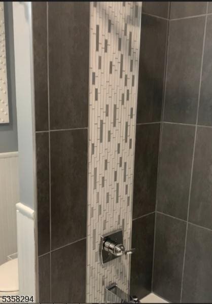 bathroom featuring a tile shower and wainscoting