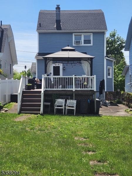 back of property with a gazebo, a deck, and a chimney