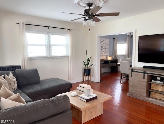 living room with dark wood-type flooring and a ceiling fan