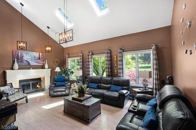 67 Brookwood Rd, Byram Twp, NJ 07874 - living room with high vaulted ceiling, a chandelier, a skylight, light wood finished floors, and a high end fireplace