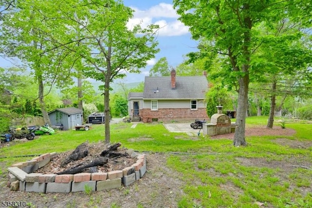 104 Lake Park Ter, West Milford Twp, NJ 07421 - view of green lawn with an outdoor fire pit, a storage unit, an outdoor structure, and a patio