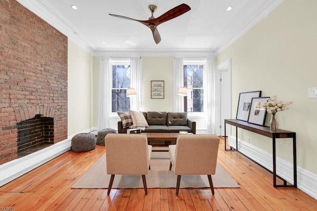 living area with light wood-type flooring, ceiling fan, crown molding, a brick fireplace, and recessed lighting