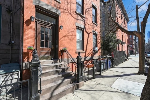 property entrance with brick siding and fence