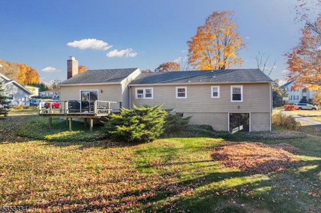 rear view of house with a wooden deck, a lawn, and a chimney