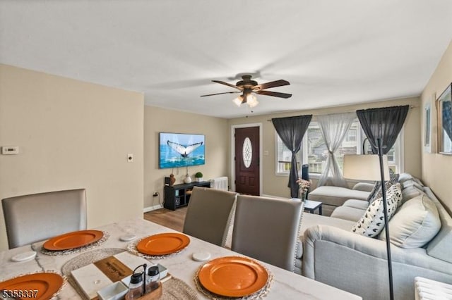 dining room featuring a ceiling fan, radiator heating unit, and wood finished floors