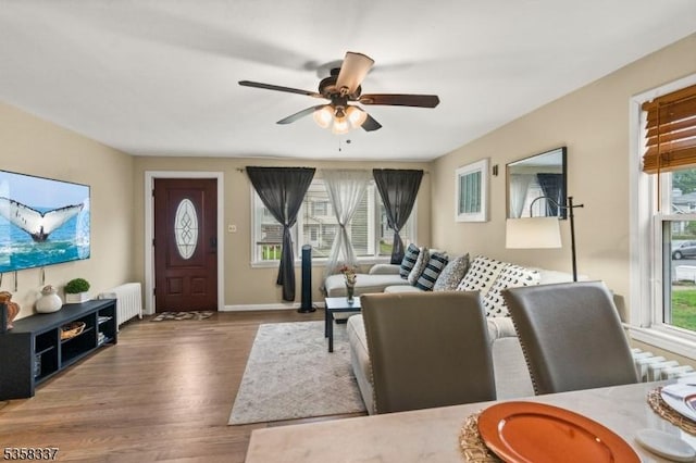 living area with wood finished floors, radiator heating unit, a ceiling fan, and baseboards