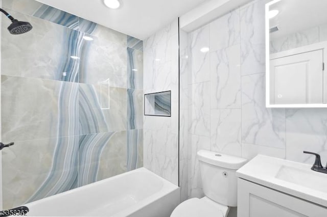 bathroom with tile walls, toilet, vanity, and tub / shower combination
