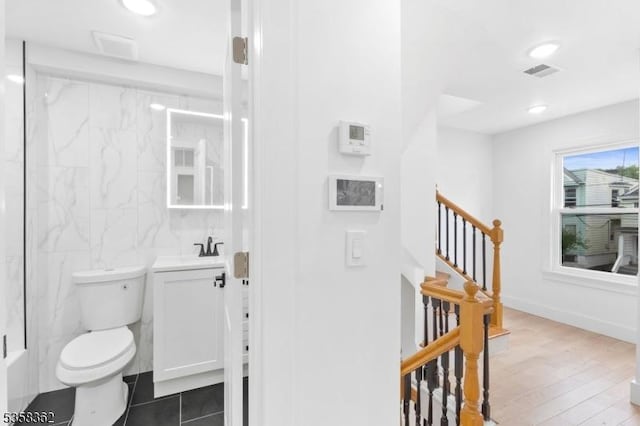 full bath featuring toilet, tile walls, vanity, recessed lighting, and a shower