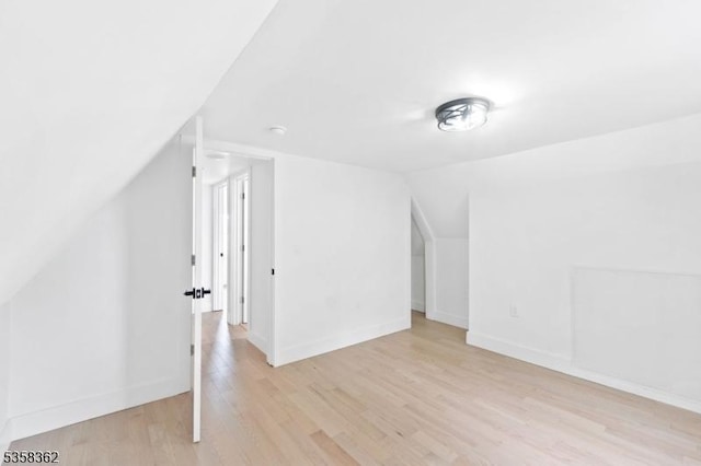 bonus room featuring lofted ceiling, light wood-style floors, and baseboards