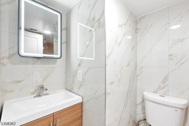 bathroom with tile walls, vanity, and toilet