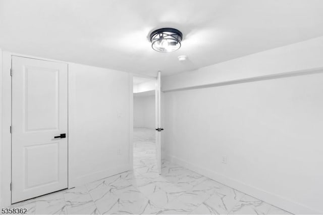 bathroom with marble look tile flooring and baseboards