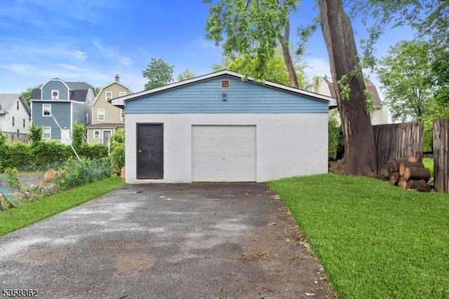detached garage with fence and asphalt driveway