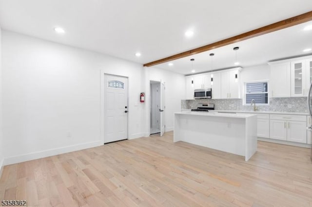 kitchen featuring stainless steel appliances, decorative backsplash, beam ceiling, a center island, and recessed lighting