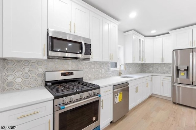 kitchen with appliances with stainless steel finishes, a sink, white cabinetry, and recessed lighting
