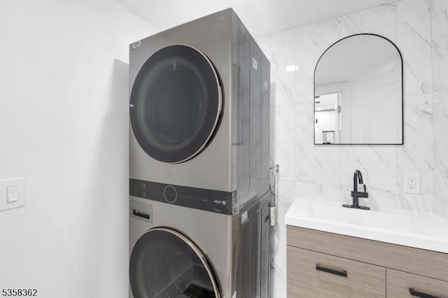 laundry area featuring stacked washer / dryer and a sink