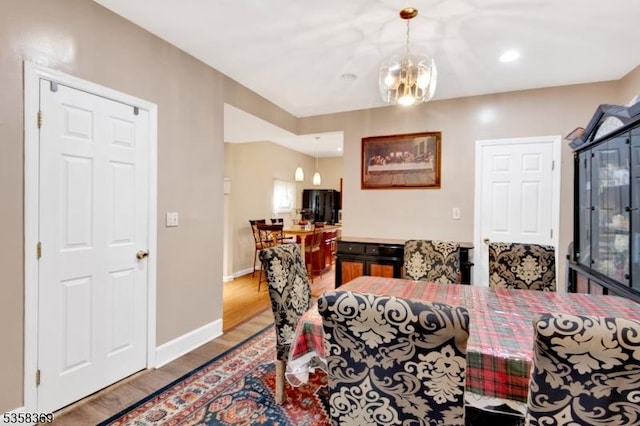 dining room featuring wood finished floors, a chandelier, and baseboards