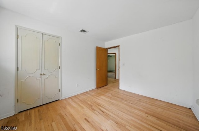 unfurnished bedroom with light wood-style flooring, a closet, and baseboards