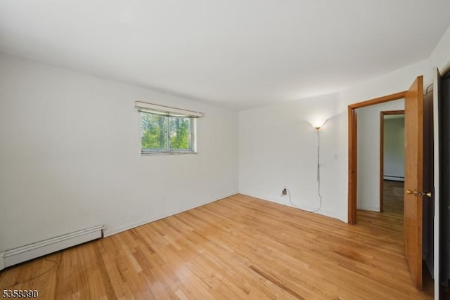 spare room featuring baseboard heating and light wood-type flooring