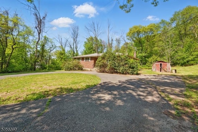 view of front of house featuring a shed, a front lawn, and an outbuilding
