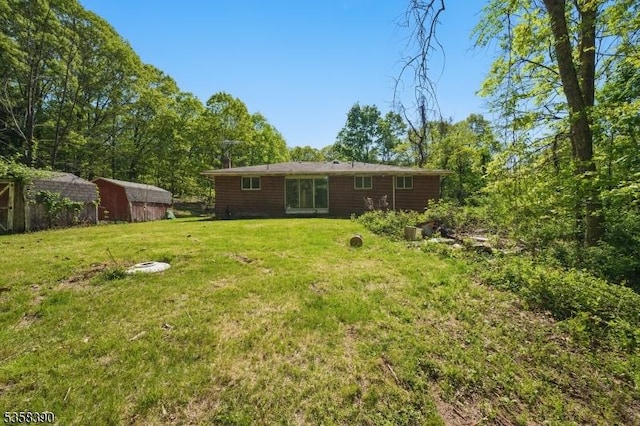 back of property with a shed, a yard, and an outbuilding