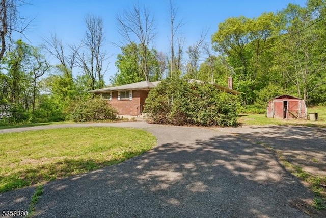view of front of house featuring a shed, an outdoor structure, a front yard, and brick siding