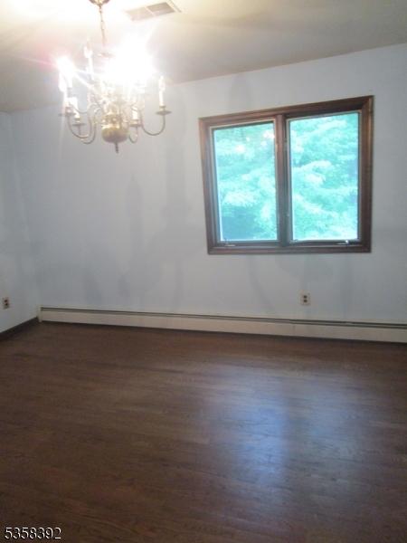 1601 Justin Pl, Mountainside Boro, NJ 07092 - unfurnished room featuring baseboard heating, a chandelier, and dark wood finished floors