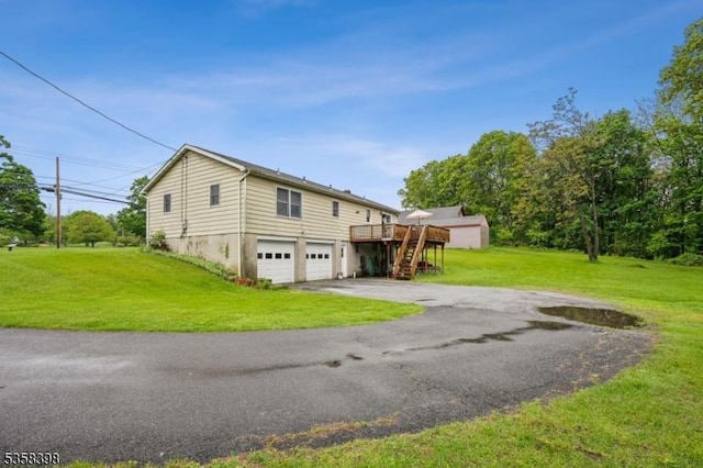 view of side of property with driveway, an attached garage, a wooden deck, a lawn, and stairway