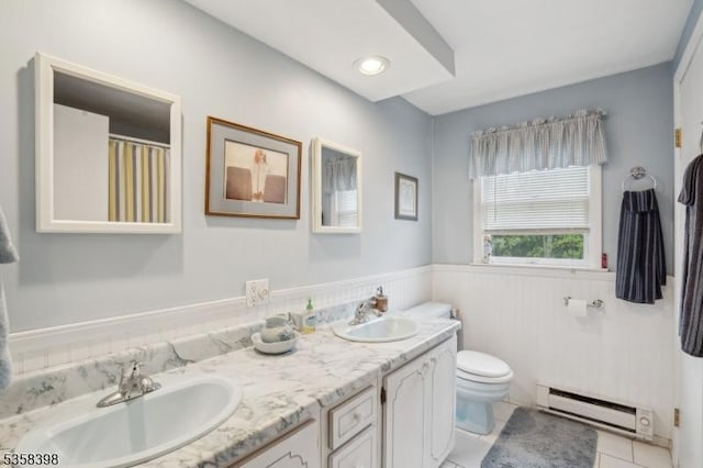 bathroom featuring a baseboard radiator, a wainscoted wall, toilet, tile patterned flooring, and double vanity