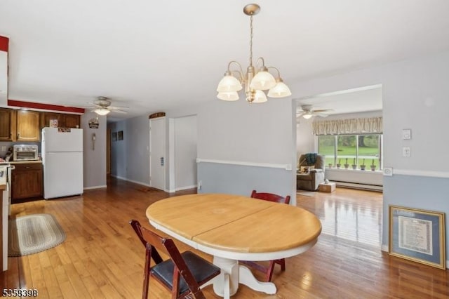 dining area featuring ceiling fan, light wood-style floors, a chandelier, and baseboard heating