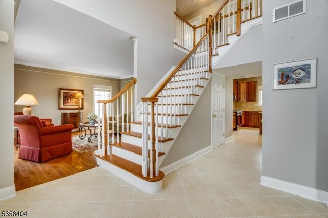 9 Colgate Ct, Franklin Twp, NJ 08873 - stairway with baseboards, tile patterned flooring, ornamental molding, and a towering ceiling