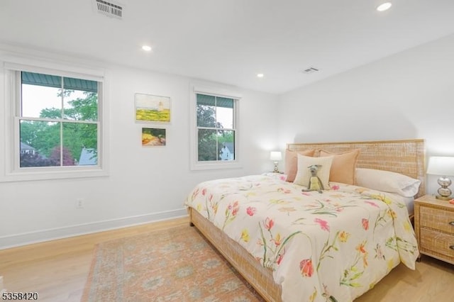 bedroom with multiple windows, light wood finished floors, recessed lighting, and baseboards