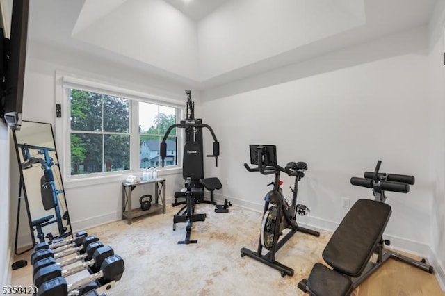 workout area with a raised ceiling and baseboards