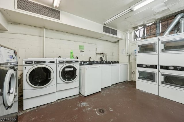 shared laundry featuring washer and dryer, stacked washer and clothes dryer, and concrete block wall