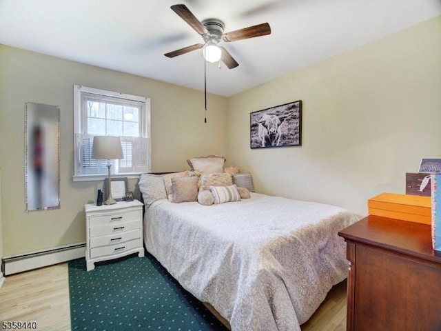 bedroom featuring baseboard heating, wood finished floors, and ceiling fan