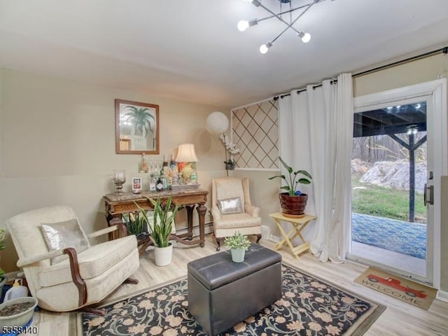 living area featuring wood finished floors, a chandelier, and baseboards