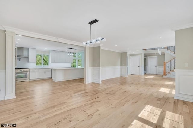 737 Wingate Dr, Bridgewater Twp, NJ 08807 - unfurnished living room with crown molding, a decorative wall, light wood-style flooring, a wainscoted wall, and a chandelier