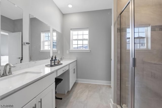 bathroom with a shower stall, double vanity, and baseboards