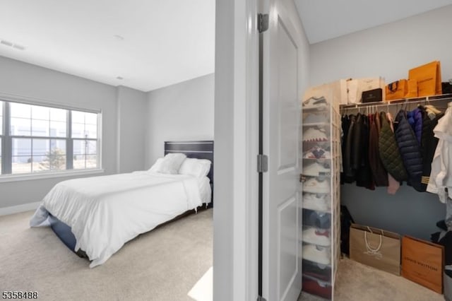 carpeted bedroom with a closet, a spacious closet, and baseboards