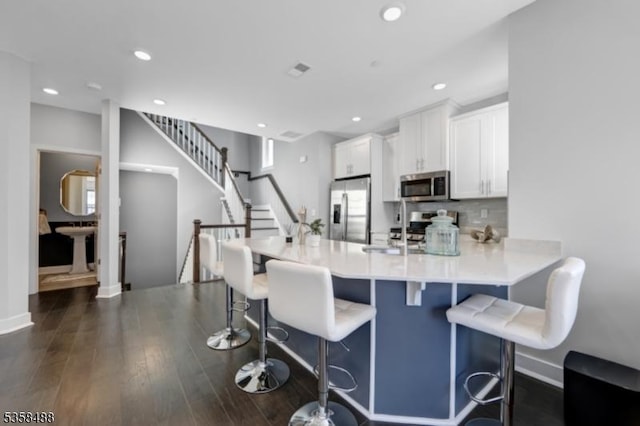 kitchen featuring appliances with stainless steel finishes, white cabinets, a peninsula, recessed lighting, and light countertops