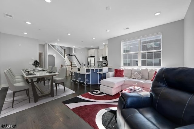 living area featuring recessed lighting, dark wood-style floors, and stairway