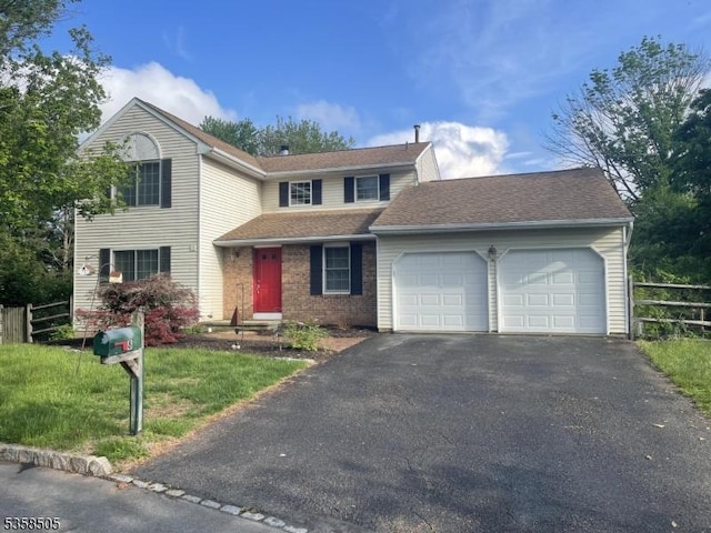 traditional-style house with fence, an attached garage, and asphalt driveway