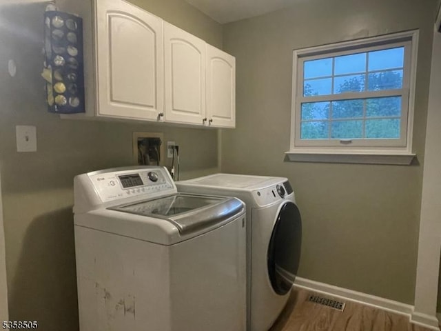 laundry room featuring cabinet space, separate washer and dryer, baseboards, and wood finished floors