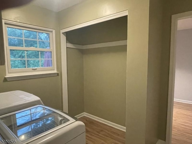 clothes washing area featuring wood finished floors and baseboards
