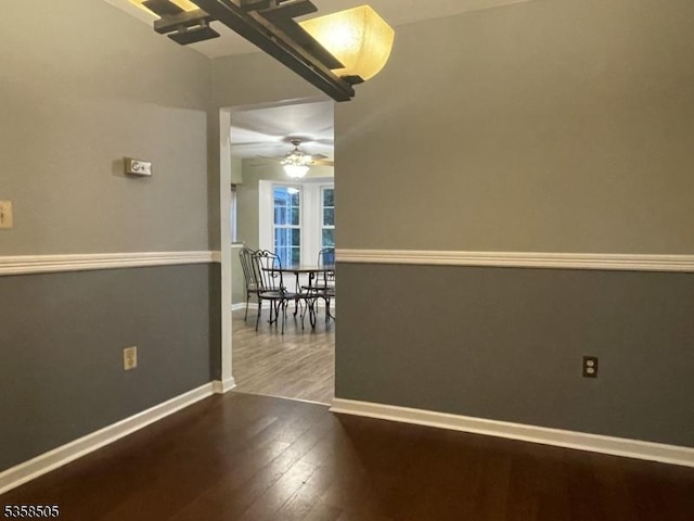 empty room with wood finished floors, baseboards, and ceiling fan