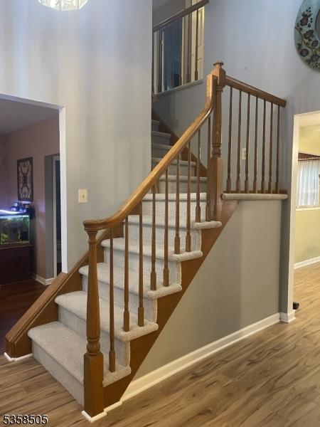stairway featuring wood finished floors, a towering ceiling, and baseboards