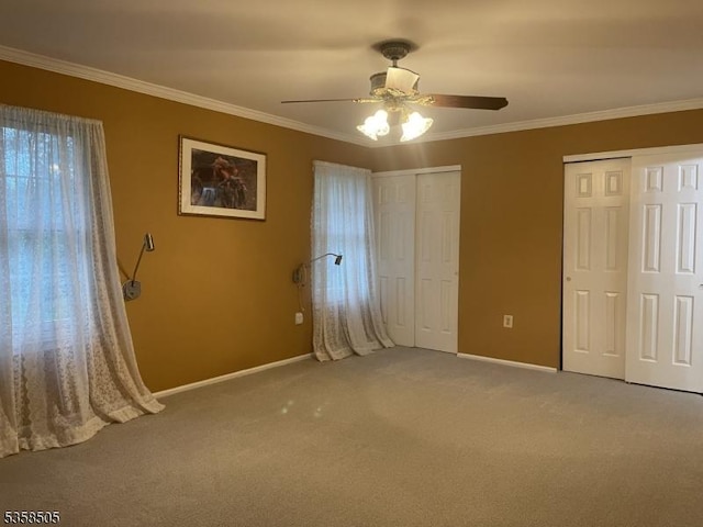 unfurnished bedroom featuring two closets, baseboards, carpet floors, ornamental molding, and a ceiling fan