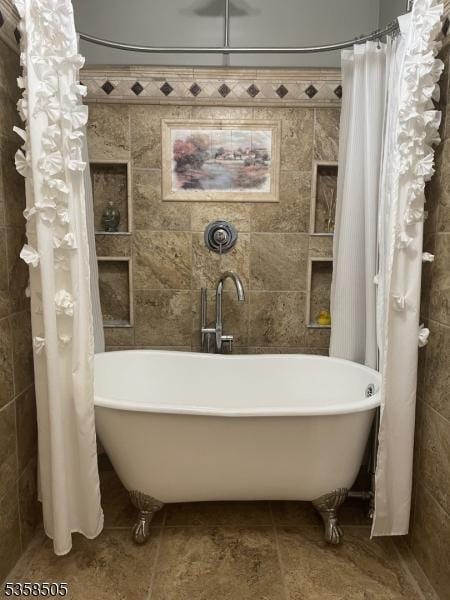 full bath with a freestanding tub and tile walls