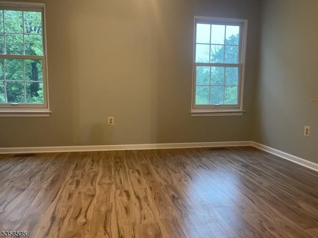 spare room featuring healthy amount of natural light, wood finished floors, and baseboards
