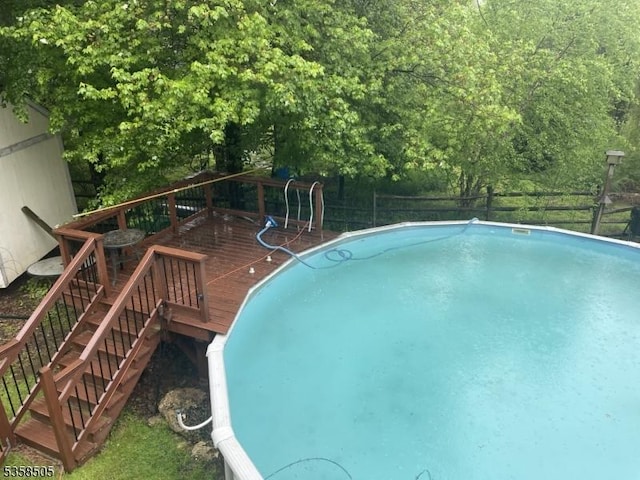 swimming pool featuring a wooden deck, fence, and stairs